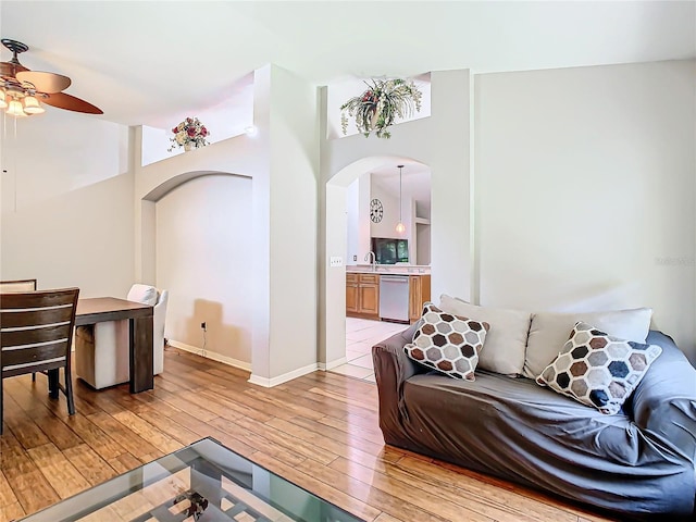 living room featuring light hardwood / wood-style flooring, lofted ceiling, ceiling fan, and sink