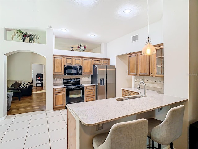 kitchen featuring sink, a kitchen breakfast bar, kitchen peninsula, and black appliances