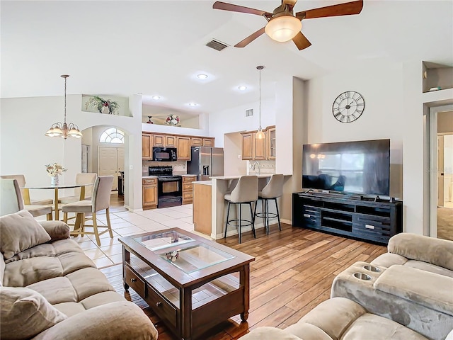 living room with ceiling fan, sink, light hardwood / wood-style floors, and a high ceiling