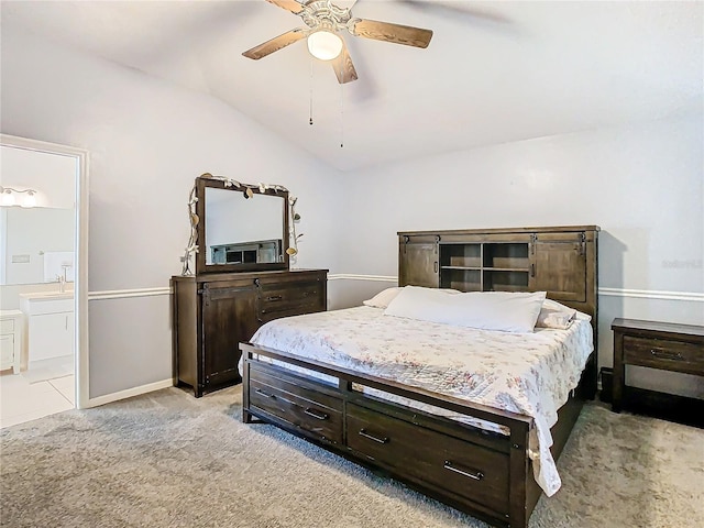 bedroom featuring ceiling fan, light colored carpet, vaulted ceiling, and ensuite bathroom