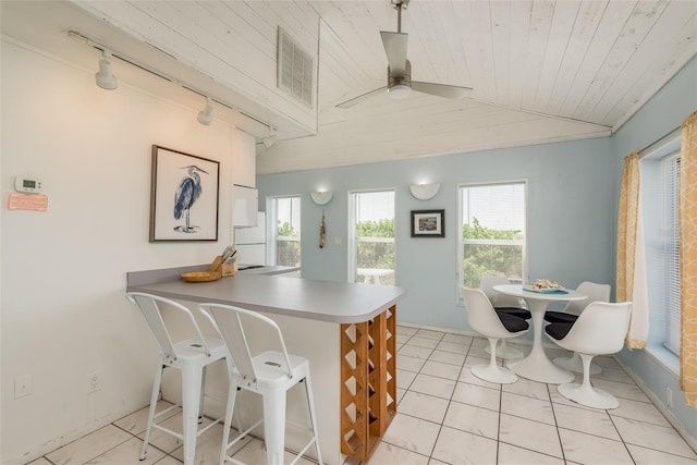 kitchen featuring ceiling fan, lofted ceiling, wood ceiling, light tile patterned floors, and kitchen peninsula