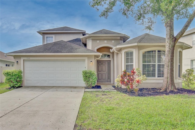 7110 Moss Ledge Run, Land O Lakes, FL 34637 - view of front of property featuring stucco siding, a shingled roof, driveway, a front yard, and an attached garage