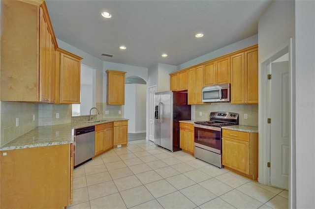 7110 Moss Ledge Run, Land O Lakes, FL 34637 - kitchen featuring light stone countertops, a sink, tasteful backsplash, arched walkways, and appliances with stainless steel finishes