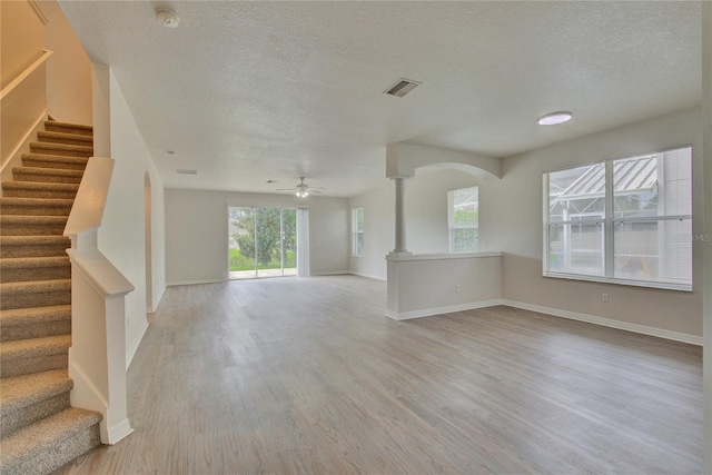 7110 Moss Ledge Run, Land O Lakes, FL 34637 - unfurnished living room featuring a textured ceiling, ceiling fan, visible vents, light wood-style floors, and stairs