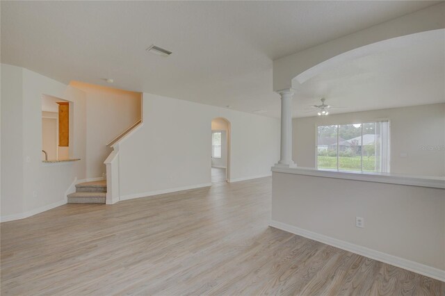 7110 Moss Ledge Run, Land O Lakes, FL 34637 - unfurnished living room featuring visible vents, baseboards, arched walkways, light wood-type flooring, and ornate columns