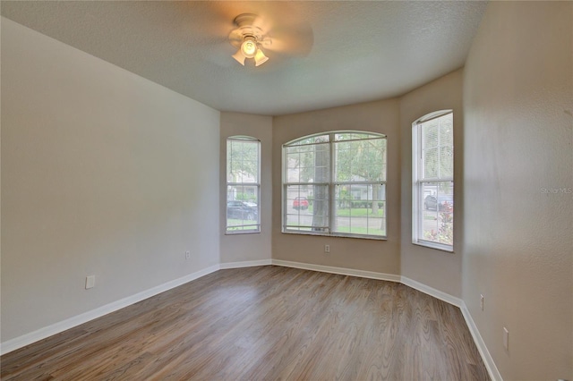 7110 Moss Ledge Run, Land O Lakes, FL 34637 - unfurnished room featuring a ceiling fan, a textured ceiling, wood finished floors, and baseboards
