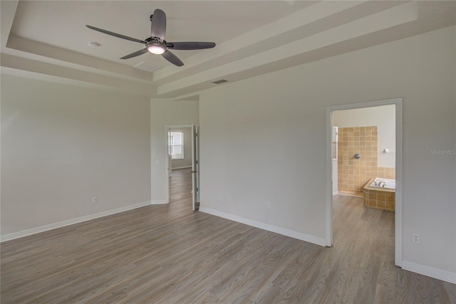 7110 Moss Ledge Run, Land O Lakes, FL 34637 - unfurnished room featuring visible vents, a tray ceiling, baseboards, wood finished floors, and a ceiling fan
