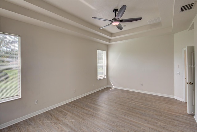 7110 Moss Ledge Run, Land O Lakes, FL 34637 - spare room featuring light wood finished floors, visible vents, ceiling fan, and a tray ceiling