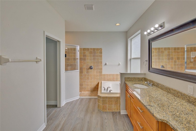 7110 Moss Ledge Run, Land O Lakes, FL 34637 - bathroom featuring visible vents, a bath, wood finished floors, vanity, and tiled shower