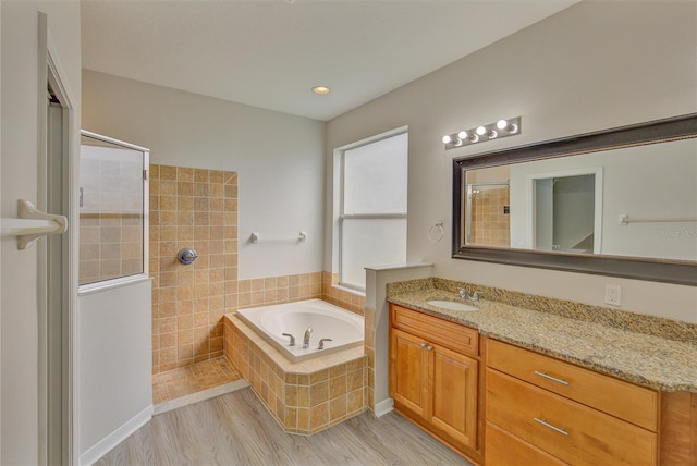 7110 Moss Ledge Run, Land O Lakes, FL 34637 - bathroom with a tile shower, a bath, wood finished floors, and vanity