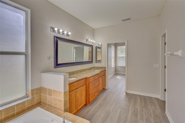 7110 Moss Ledge Run, Land O Lakes, FL 34637 - bathroom with a sink, double vanity, baseboards, wood finished floors, and a bathtub