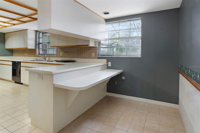 kitchen featuring dishwasher, kitchen peninsula, white cabinets, decorative backsplash, and light tile patterned floors