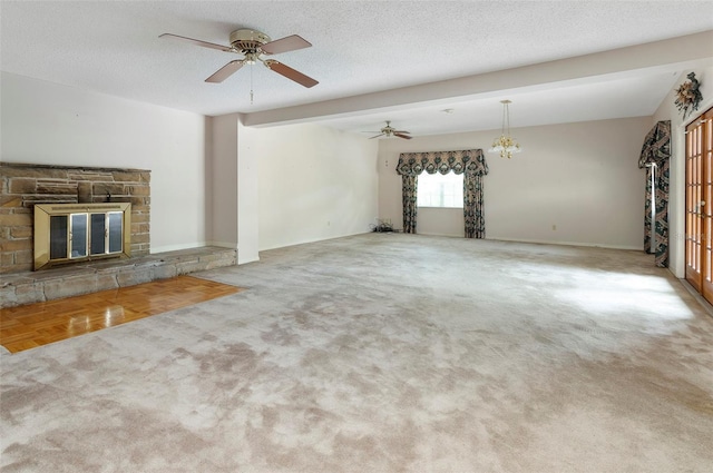 unfurnished living room with carpet, a stone fireplace, a textured ceiling, and ceiling fan