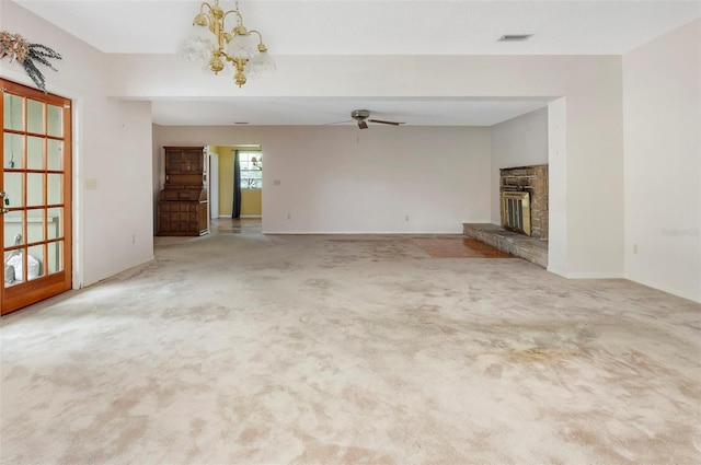 unfurnished living room featuring ceiling fan with notable chandelier, a fireplace, and light colored carpet