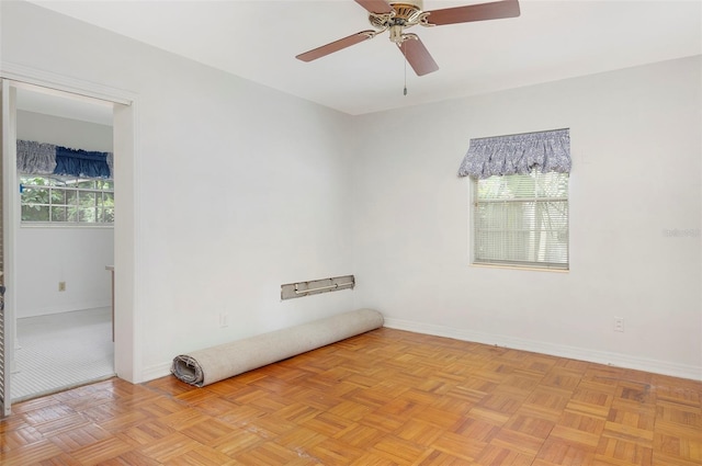 unfurnished room with a wealth of natural light, light parquet flooring, and ceiling fan