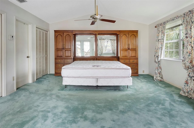 unfurnished bedroom featuring vaulted ceiling, two closets, carpet floors, and ceiling fan