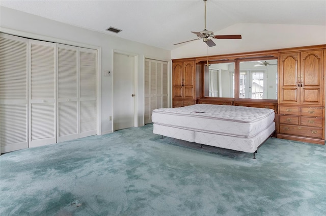 unfurnished bedroom featuring multiple closets, carpet floors, lofted ceiling, and ceiling fan