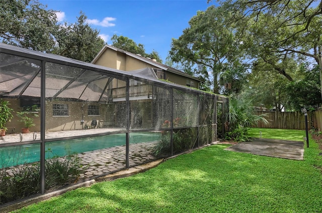 view of pool featuring glass enclosure, a patio area, and a lawn