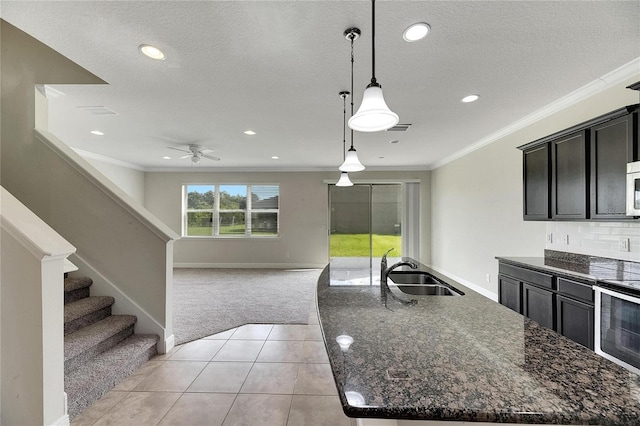 kitchen featuring a kitchen island, ceiling fan, decorative light fixtures, sink, and light carpet