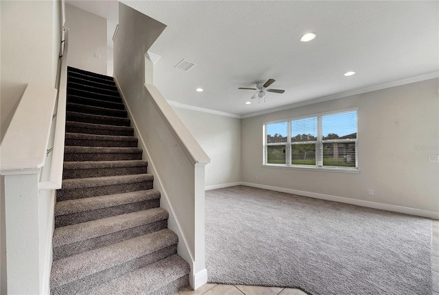 staircase with crown molding, carpet flooring, and ceiling fan