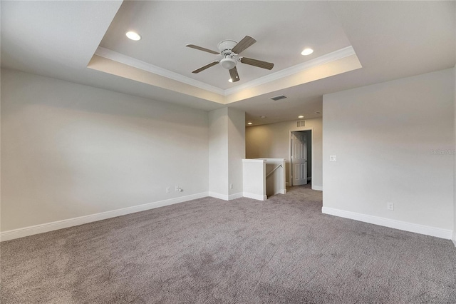 empty room featuring ornamental molding, a tray ceiling, ceiling fan, and carpet