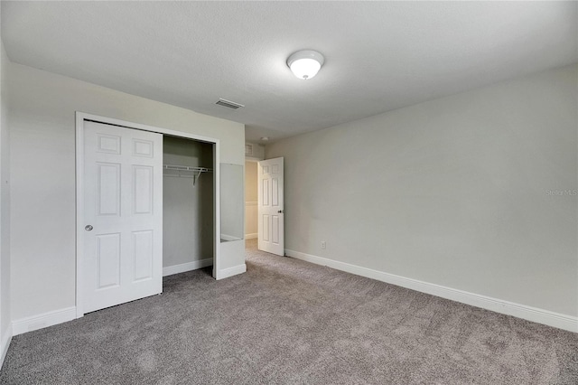 unfurnished bedroom with a textured ceiling, carpet flooring, and a closet