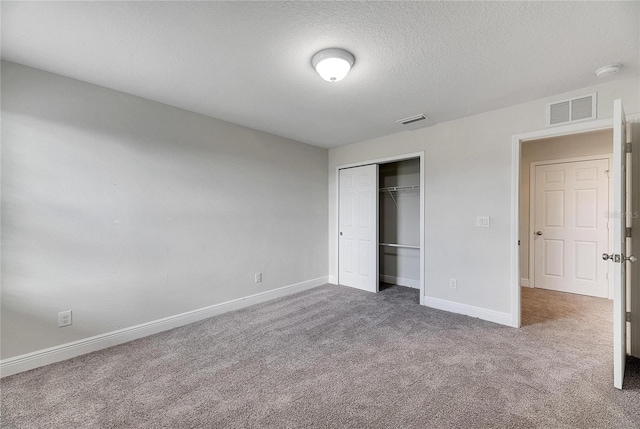 unfurnished bedroom featuring carpet floors, a textured ceiling, and a closet