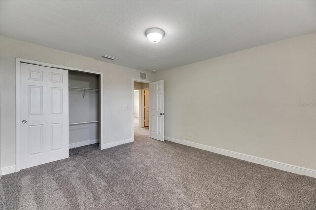 unfurnished bedroom with a textured ceiling, carpet flooring, and a closet