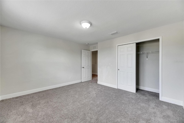 unfurnished bedroom with a textured ceiling, a closet, and carpet