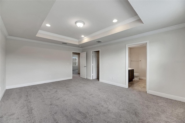 carpeted empty room with a raised ceiling and ornamental molding