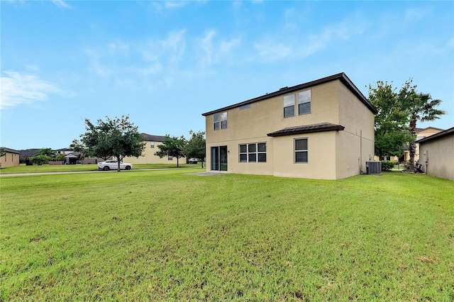 rear view of property featuring a lawn and central AC