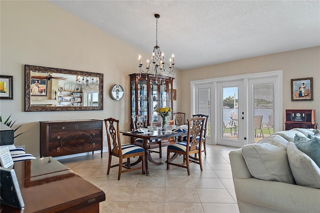 dining room featuring french doors, ceiling fan with notable chandelier, a textured ceiling, light tile patterned floors, and lofted ceiling