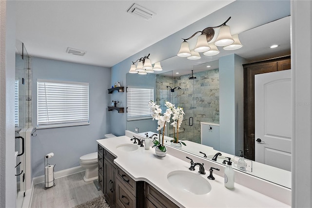 bathroom featuring vanity, wood-type flooring, a shower with shower door, and toilet