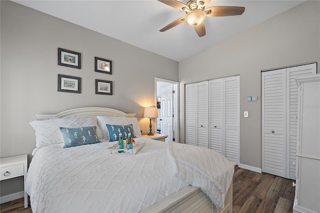 bedroom featuring ceiling fan, two closets, dark wood-type flooring, and vaulted ceiling