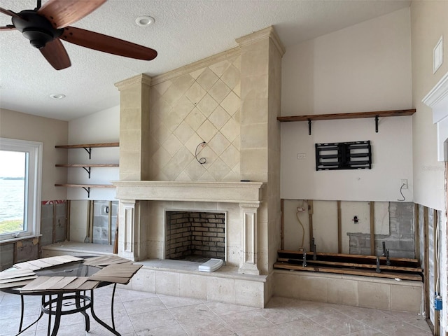 living room with a fireplace, light tile patterned floors, a textured ceiling, and ceiling fan