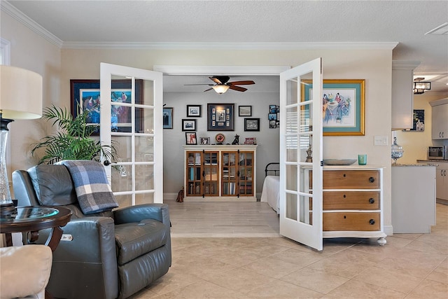 living area with a textured ceiling, ceiling fan, light tile patterned floors, and crown molding