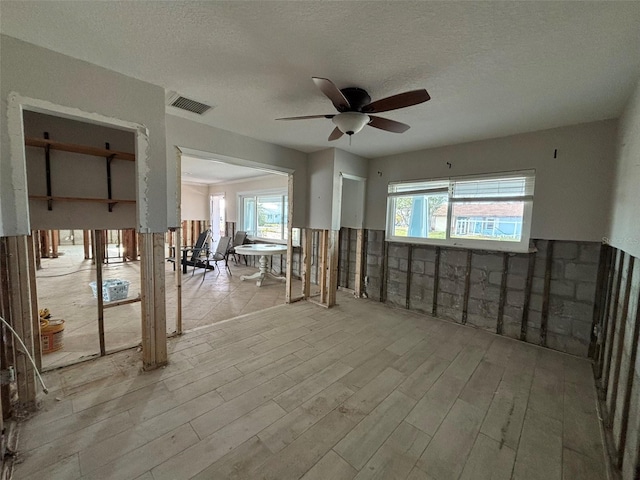 interior space with ceiling fan, light wood-type flooring, and a textured ceiling