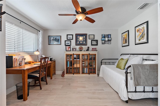 home office featuring ceiling fan, light hardwood / wood-style flooring, and a textured ceiling