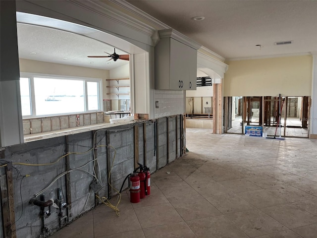 kitchen featuring crown molding, ceiling fan, decorative backsplash, light tile patterned floors, and a textured ceiling