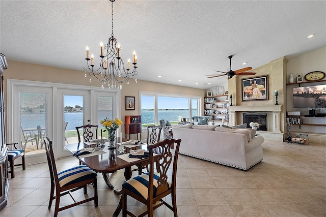 dining room featuring a textured ceiling, ceiling fan with notable chandelier, a fireplace, and french doors