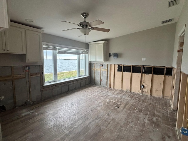 spare room with a water view, dark hardwood / wood-style floors, and ceiling fan