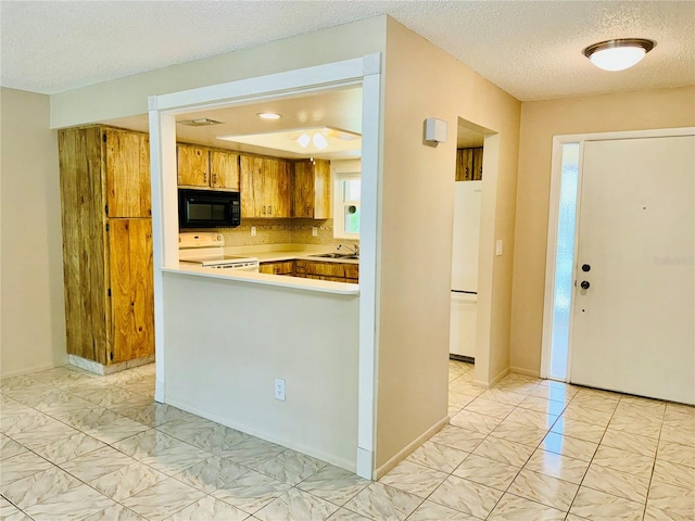 kitchen with white appliances, tasteful backsplash, a textured ceiling, kitchen peninsula, and sink