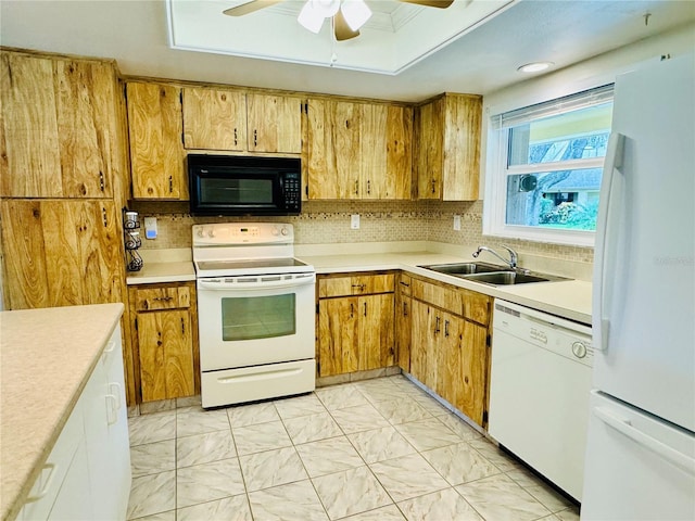 kitchen featuring white appliances, sink, a tray ceiling, ceiling fan, and decorative backsplash