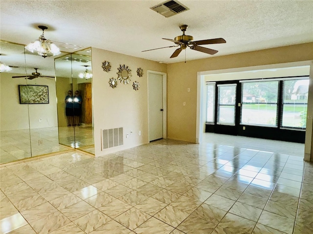 unfurnished room with a textured ceiling, ceiling fan with notable chandelier, and light tile patterned flooring