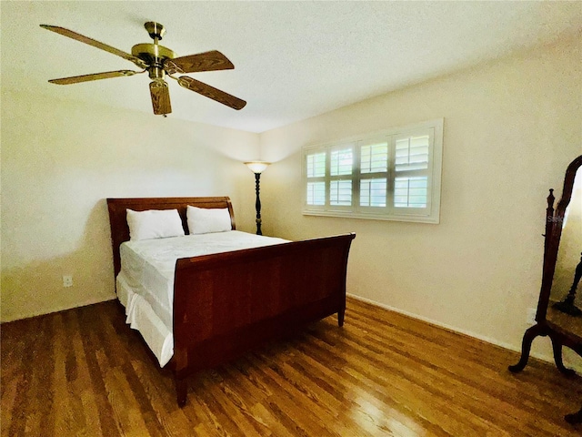 bedroom featuring dark wood-type flooring, a textured ceiling, and ceiling fan