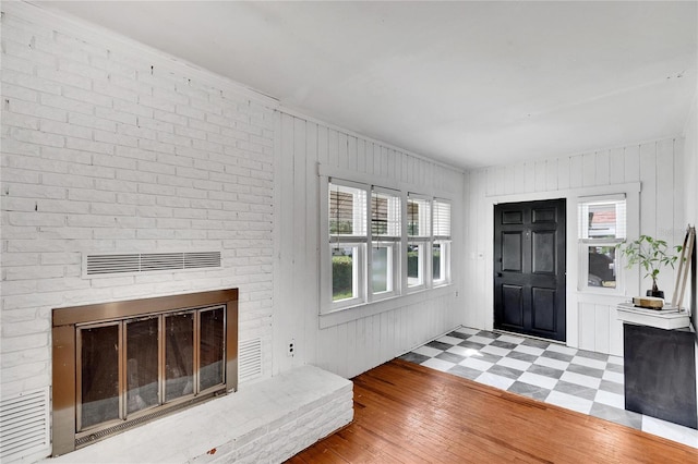 foyer entrance with a brick fireplace and hardwood / wood-style flooring