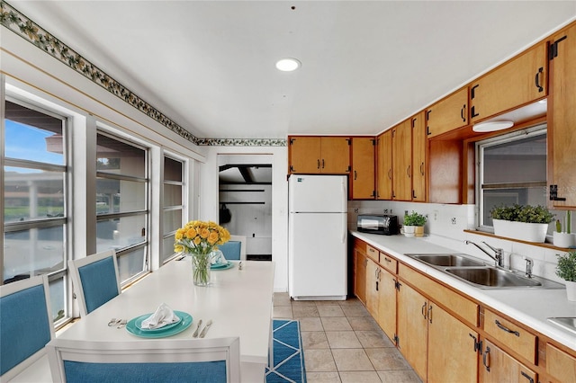 kitchen with light tile patterned floors, tasteful backsplash, white fridge, and sink