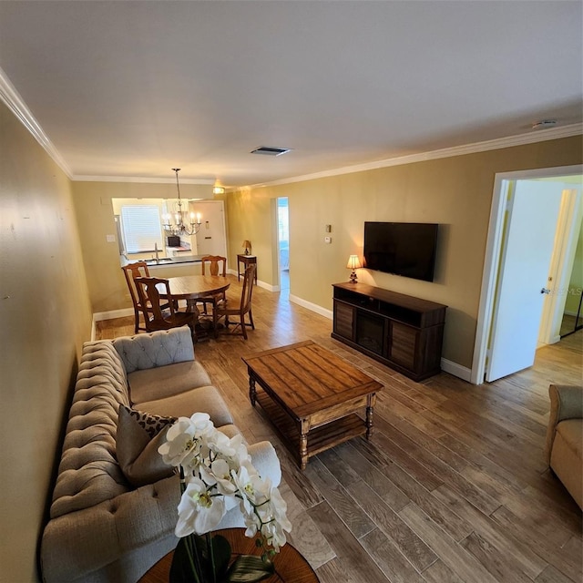 living room with wood-type flooring, crown molding, and a chandelier