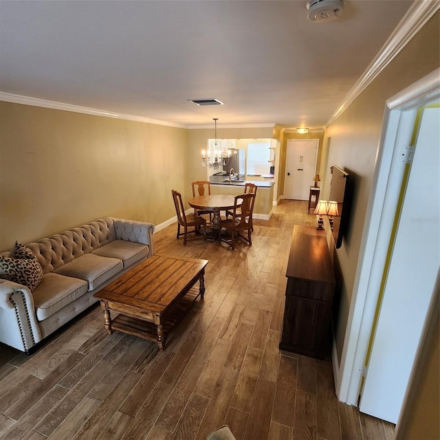 living room with wood-type flooring, crown molding, and an inviting chandelier