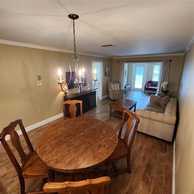 dining area with a notable chandelier, hardwood / wood-style floors, and crown molding